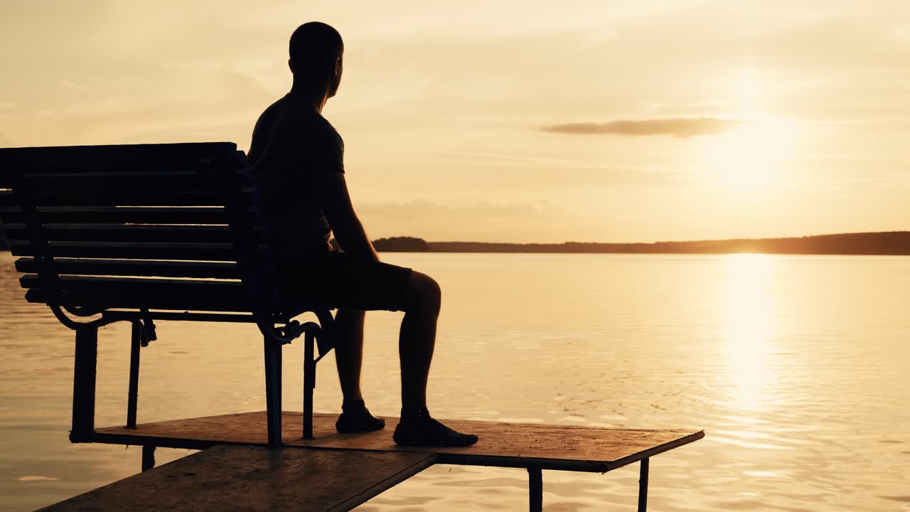 Peaceful sunset over a lake with a person sitting on a bench