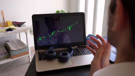joven inversor extasiado celebrando el éxito con el puño cerrado y aplaudiendo mientras mira el gráfico de velas financieras del mercado de valores en la computadora portátil