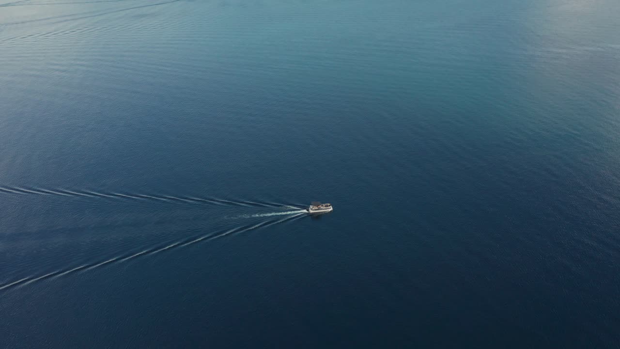 imágenes de seguimiento de drones de un barco que viaja en el lago de peces rojos rodeado de agua azul