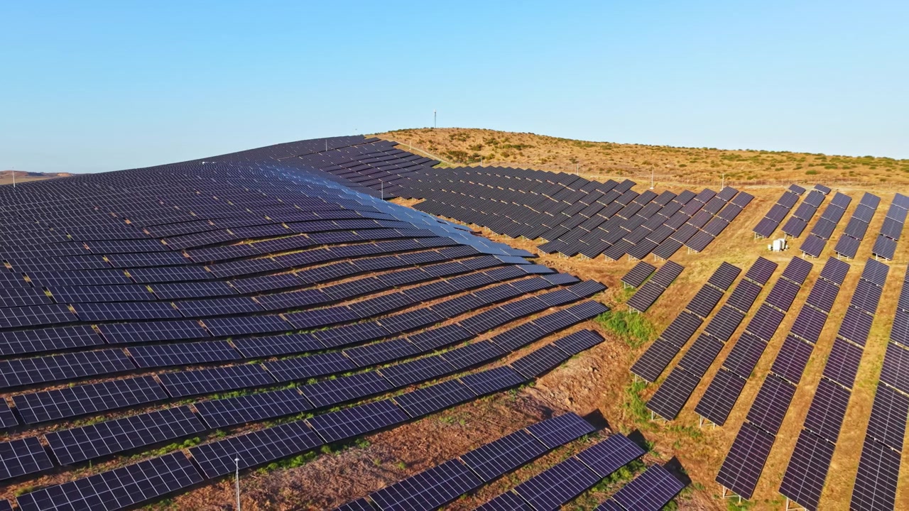 Solpaneler installeret på en bjergskråning reflekterer sollys om dagen i et vedvarende energiprojekt