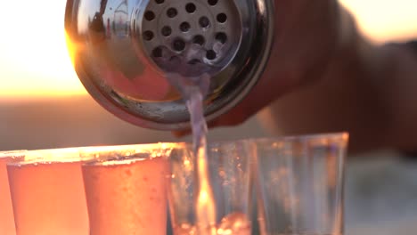 close-up pouring shots outdoors against a sunset backdrop.