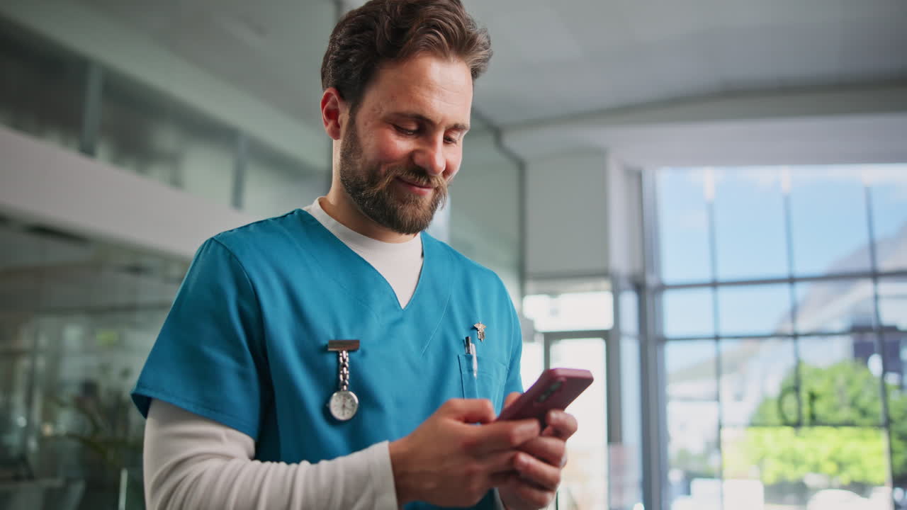 Enfermero feliz usando smartphone y sonriendo en el hospital