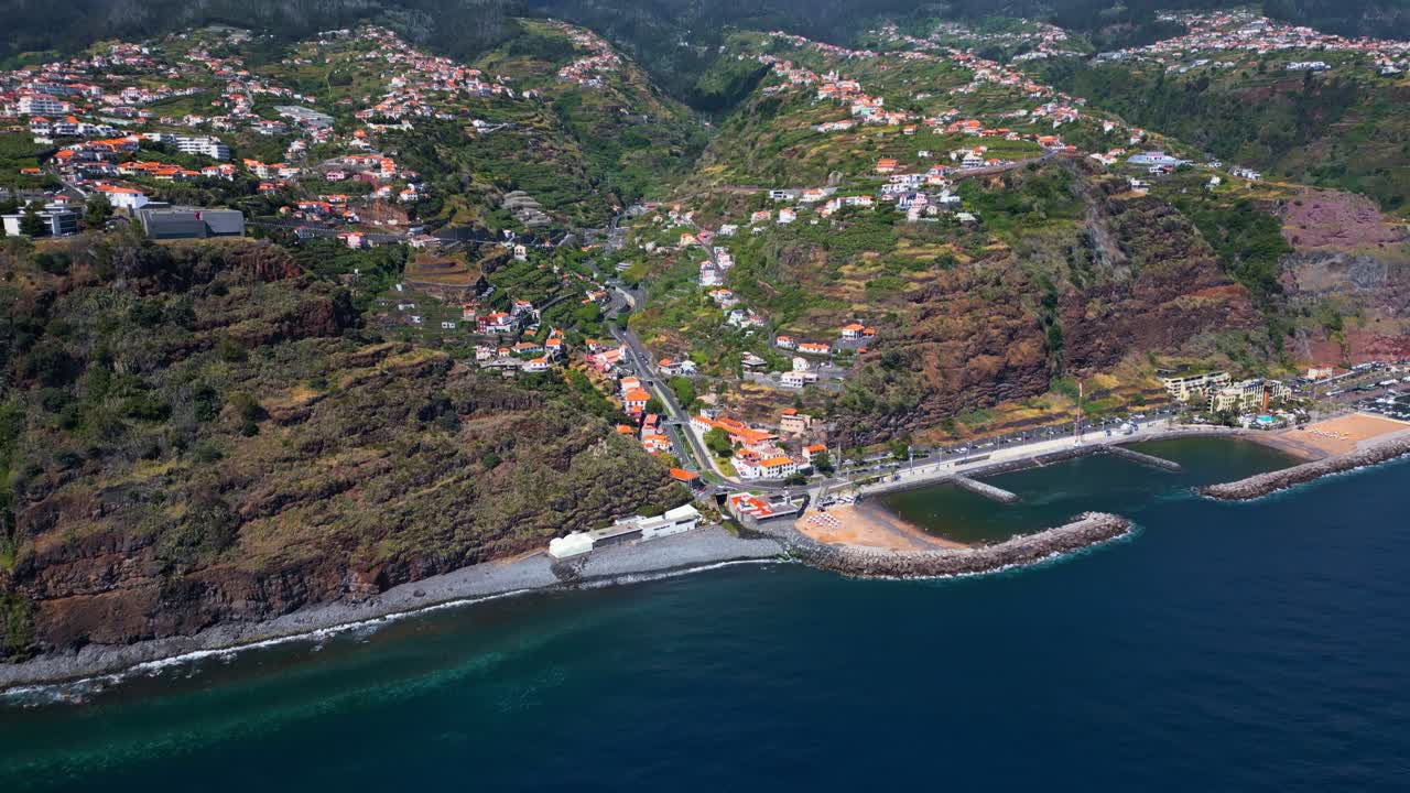 Veduta aerea panoramica di una città costiera e spiaggia su un'isola montuosa.