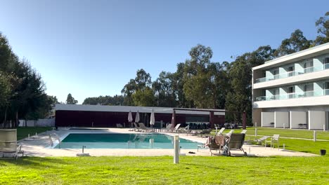 área de descanso moderna junto a la piscina en un entorno al aire libre soleado frente a un edificio - disparo de gran ángulo