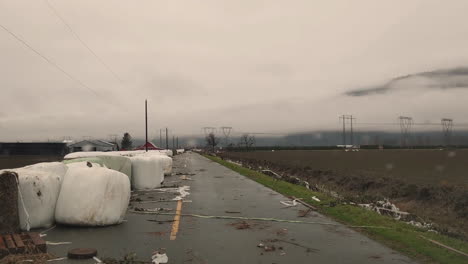 hay bales in damaged plastic wrap cover scattered on the road after flooding in abbotsford, bc, canada