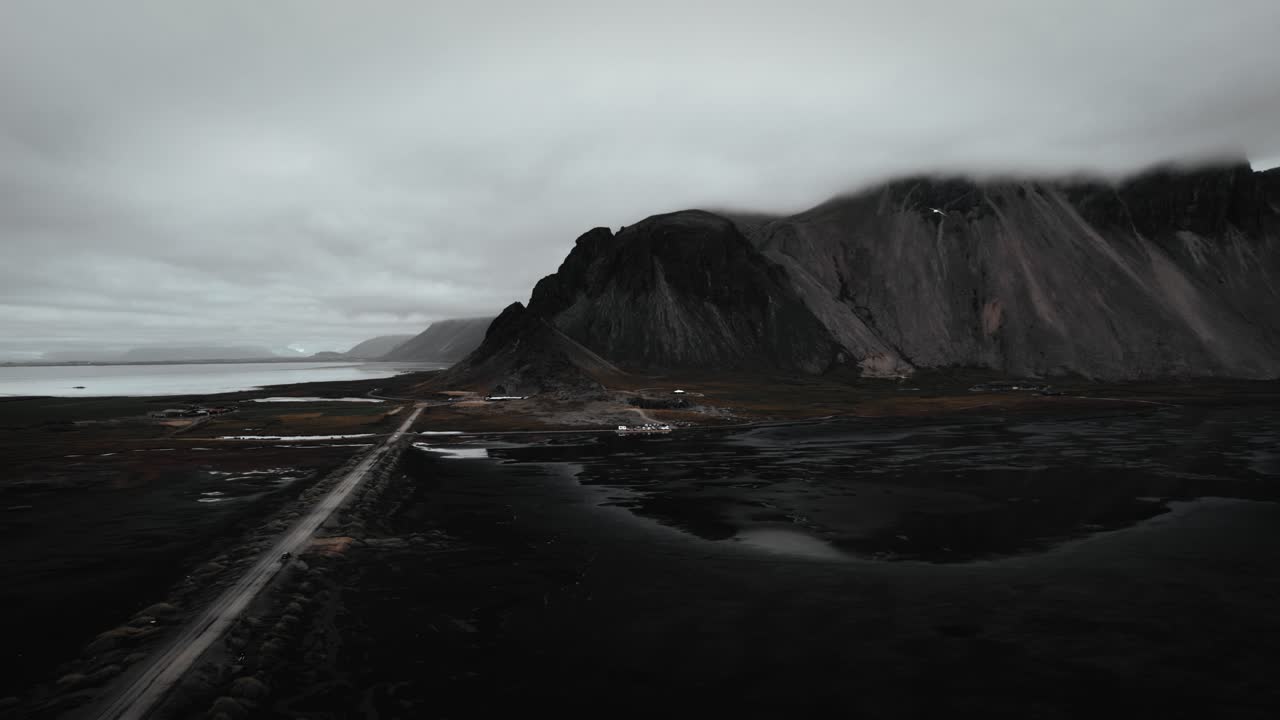 playa de arena negra aérea stokksnes, montañas volcánicas oscuras en la distancia, gaviotas oscuras de mal humor nubladas volando, islandia