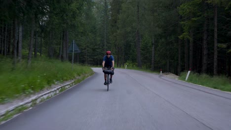 cyclist with red helmet cycling through a forest on early morning with model release, dolomites italy