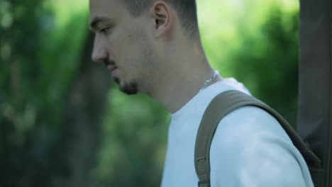 young man walking with guitar on street near forest