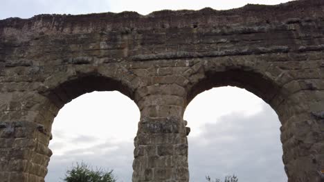 Detail-of-an-aqueduct-from-ancient-Rome-in-parco-degli-acquedotti-in-the-outskirts-of-the-capital-of-Italy,-close-up-with-a-pan-movement-combined-with-a-lateral-dolly