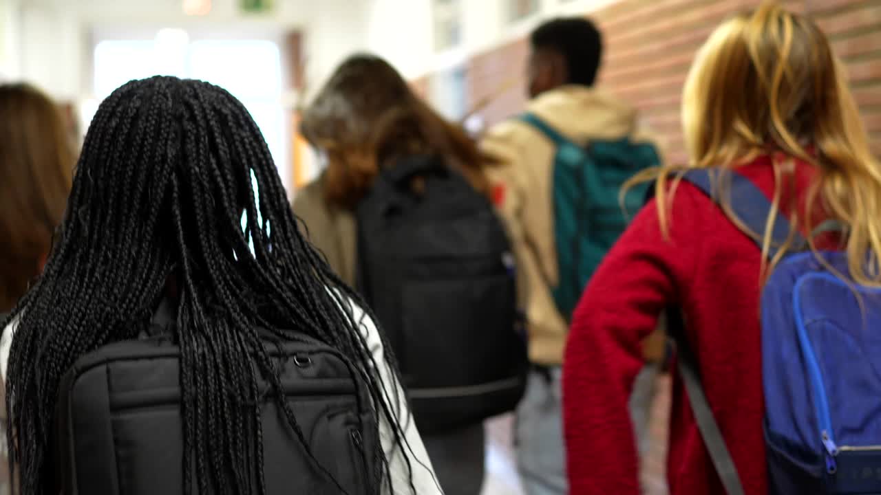 Students with backpacks walking in a school hallway