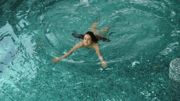 Ragazza affascinante che nuota in una piscina coperta