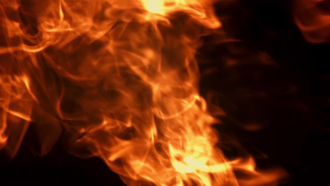 Fuego y humo rojo y naranja a cámara lenta sobre un fondo negro