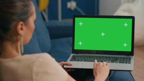 Woman-sitting-on-couch-in-cozy-living-room-working-on-laptop-computer