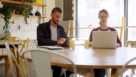 Executives-working-on-digital-tablet-and-laptop-in-cafeteria-4K-4k