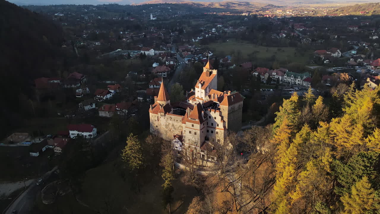 Aerial drone view of The Bran Castle in Romania. Medieval castle in Carpathians, yellowed trees, tourists, village