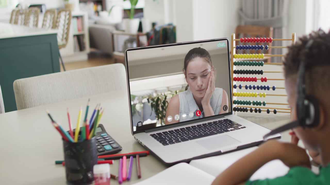 African american boy using laptop for online lesson with caucasian female teacher on screen