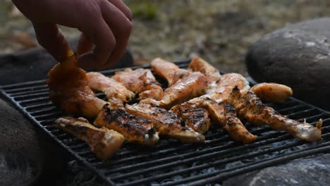 Flipping-seasoned-chicken-fillets-on-the-grill-using-hand