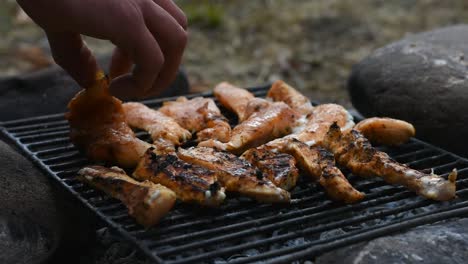 flipping seasoned chicken fillets on the grill using hand