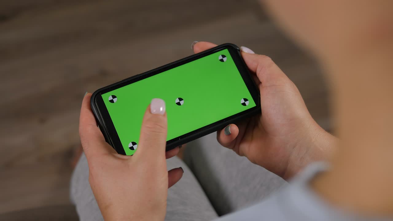 집에서 초록색 화면을 가진 드폰을 들고 있는 여성의 클로즈업입니다.