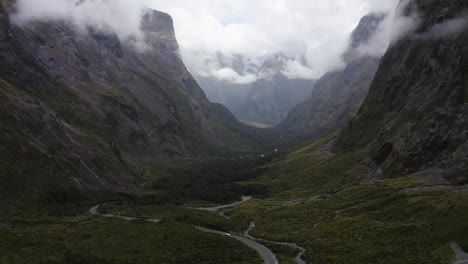 winding road passing thru the mountains, fog, and clouds in milford sound new zealand on the south island