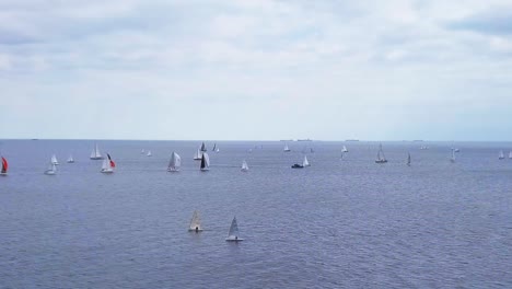 Aerial-View-Of-Sailboat-Regatta-In-A-Sea-Under-A-Cloudy-Sky