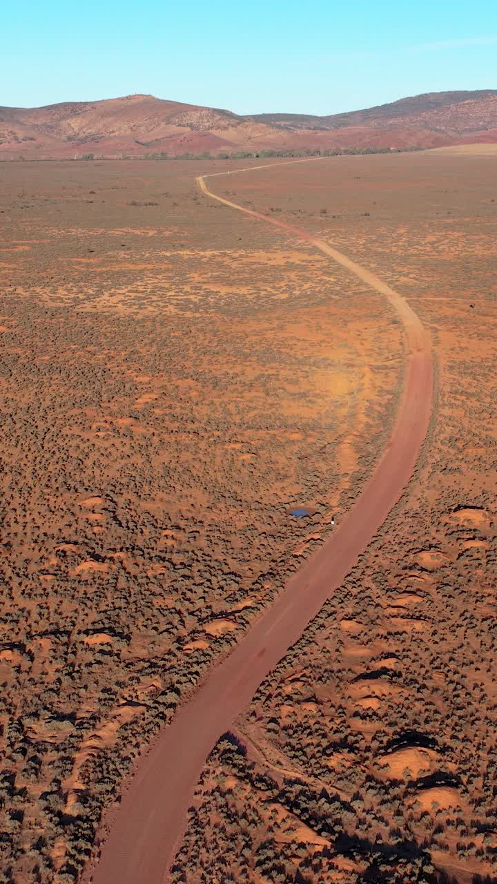 Vertical portrait drone video of dirt road in outback landscape in Flinders Ranges, South Australia