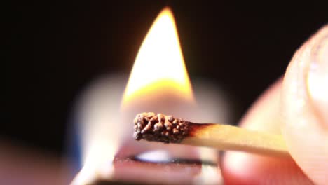 lighting a match from matchbox on black background