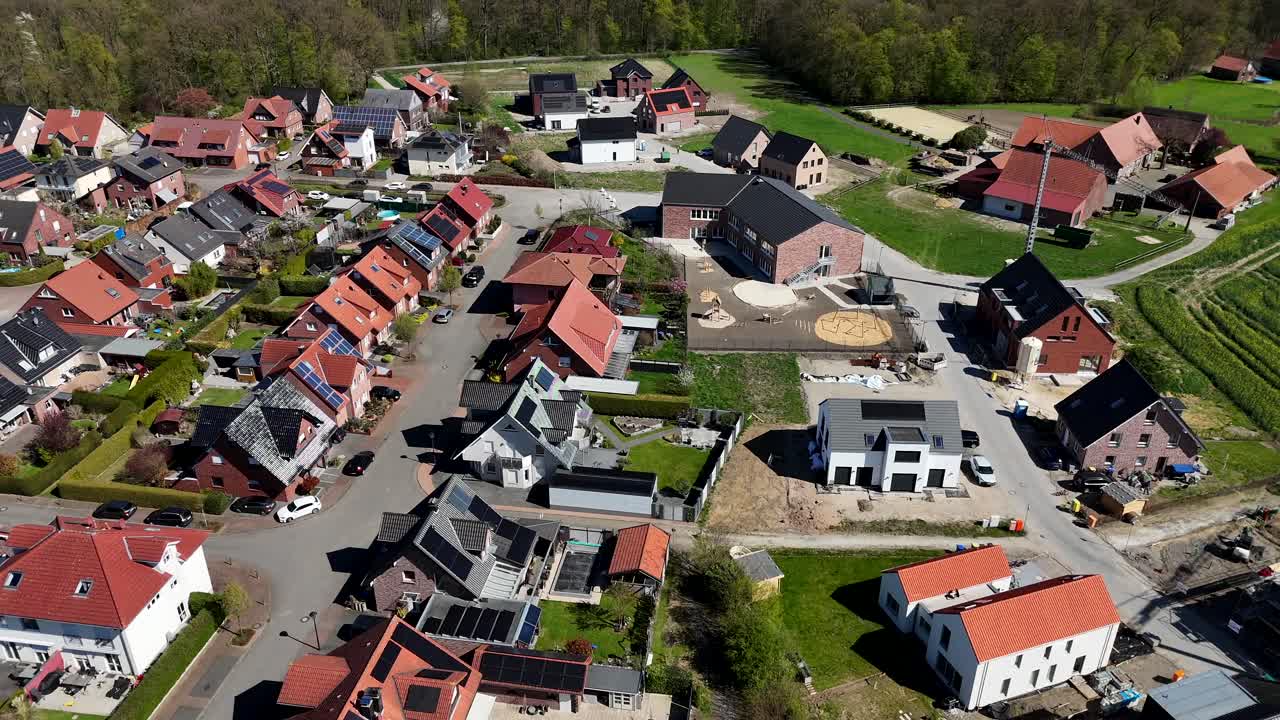 Modern new developed housing area with single family houses and solar Panels on roof in rural area. Aerial top down flyover shot. Sunny day in spring. Construction site with cranes in America.