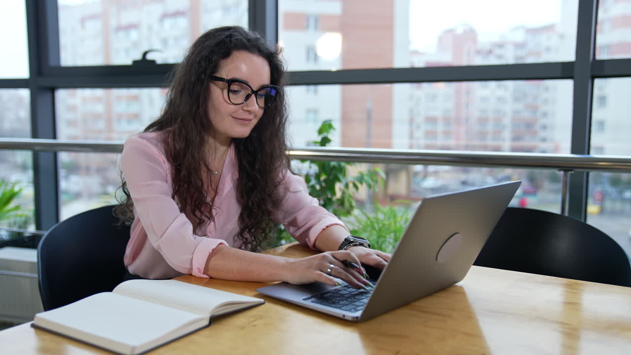 Female entrepreneur printing something on her laptop and smiling. Business correspondence with partners or clients.