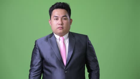 초록색 배경에 젊은 잘생긴 과체중 아시아 사업가