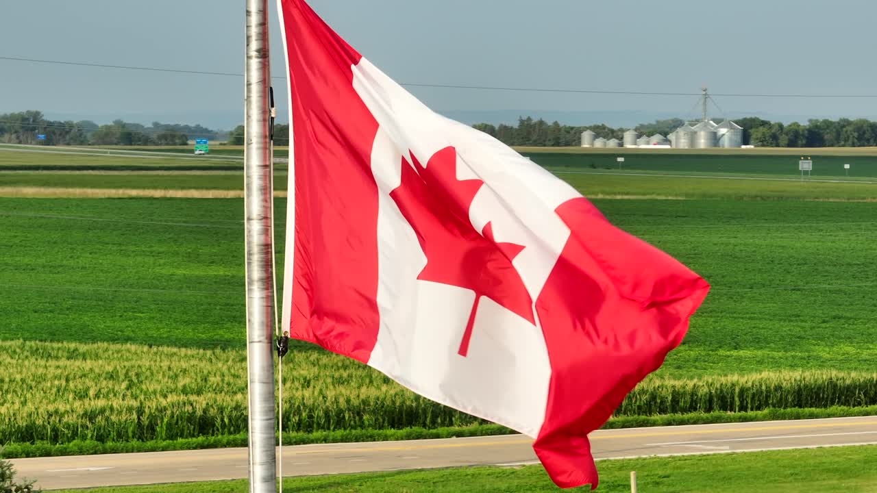 disparo estático de la bandera canadiense ondeando frente a la región agrícola en canadá