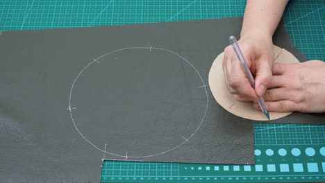 craftsman draws cutting pattern of the pouch pockets using paper shape