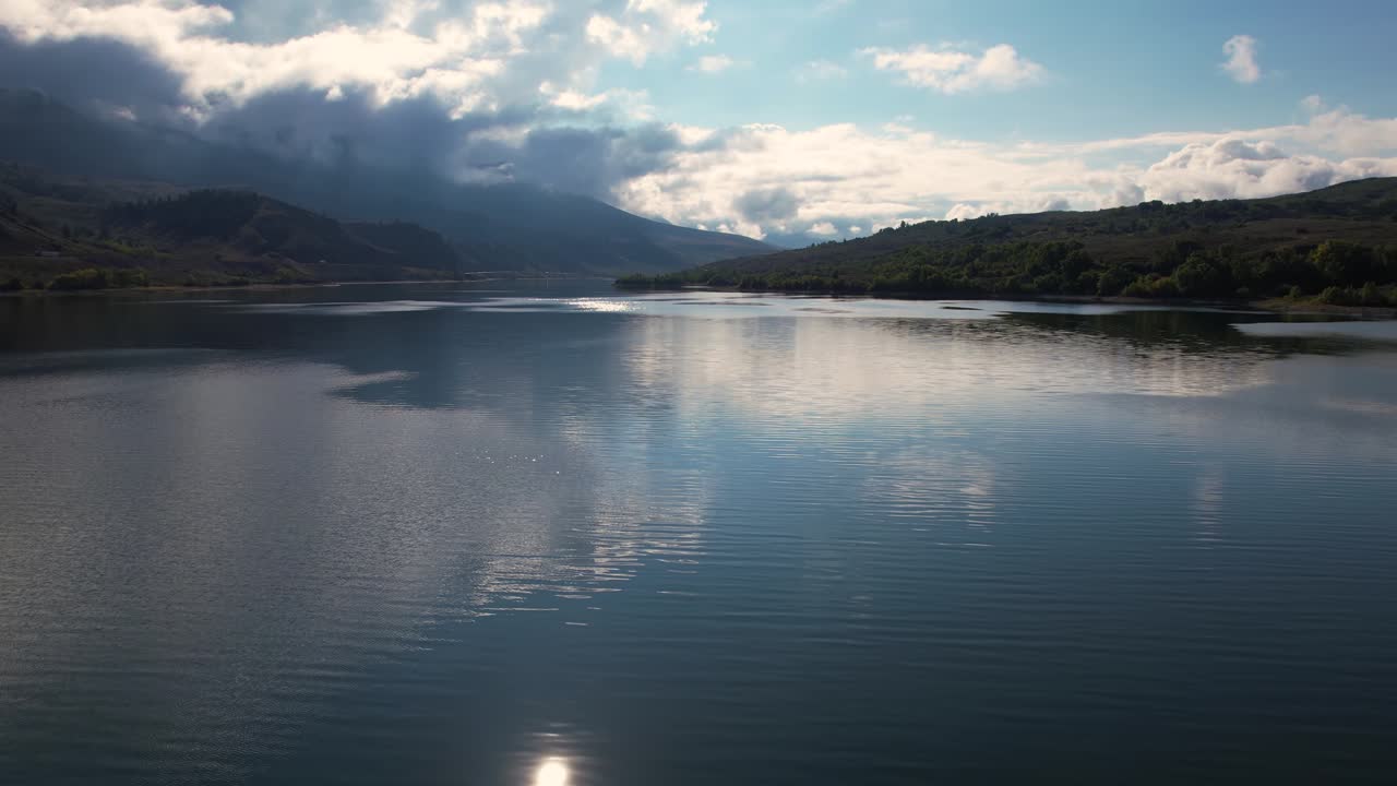 vista aérea de un hermoso lago alpino y montañas, nubes y reflejo del cielo en la superficie del agua