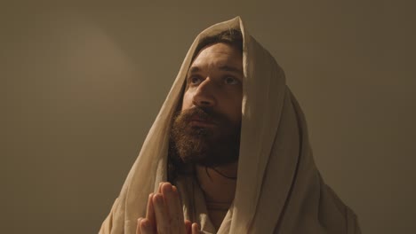 retrato de estudio de un hombre vestido con túnicas con cabello largo y barba que representa la figura de jesucristo orando 6