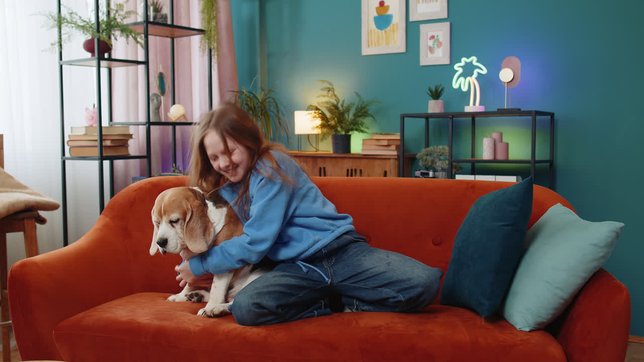 Trendy cheerful positive child girl having fun dancing moving to rhythm embracing cute beagle dog