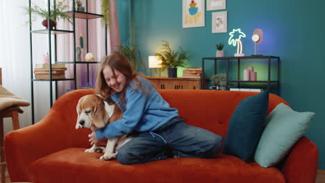 trendy cheerful positive child girl having fun dancing moving to rhythm embracing cute beagle dog