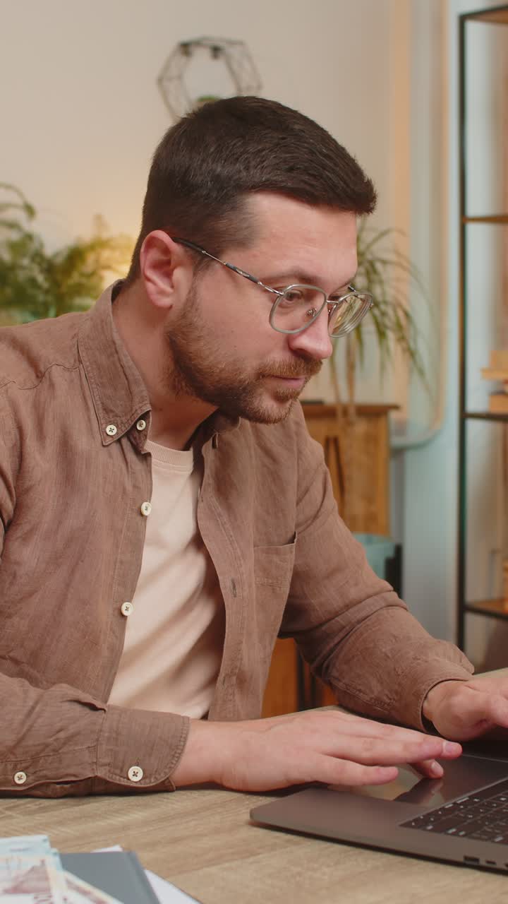 Rich happy caucasian man counting money hryvnias cash using laptop calculate domestic bills at home