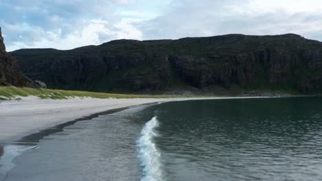 Aerial-shot-of-northern-sea-,-clear-waves-are-calmly-hitting-the-white-beach