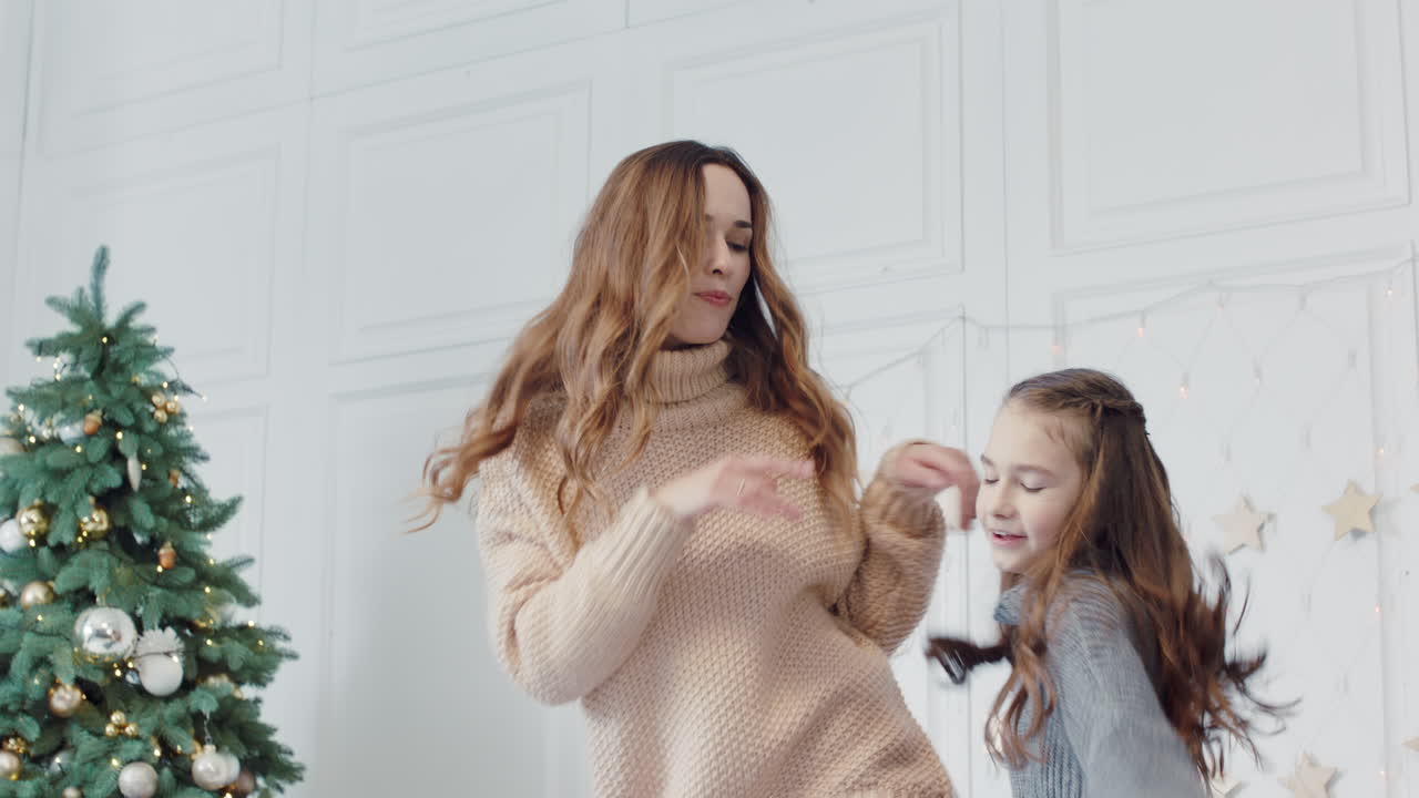 Joyful mother and daughter dancing on bed in luxury house