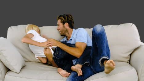 Father-tickling-son-on-the-sofa-on-grey-background