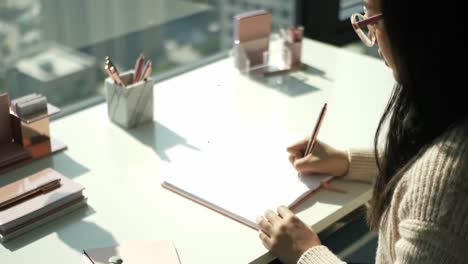 a focused writer engrossed in creative thought: capturing the essence of inspiration amidst a serene workspace filled with stationery and natural light