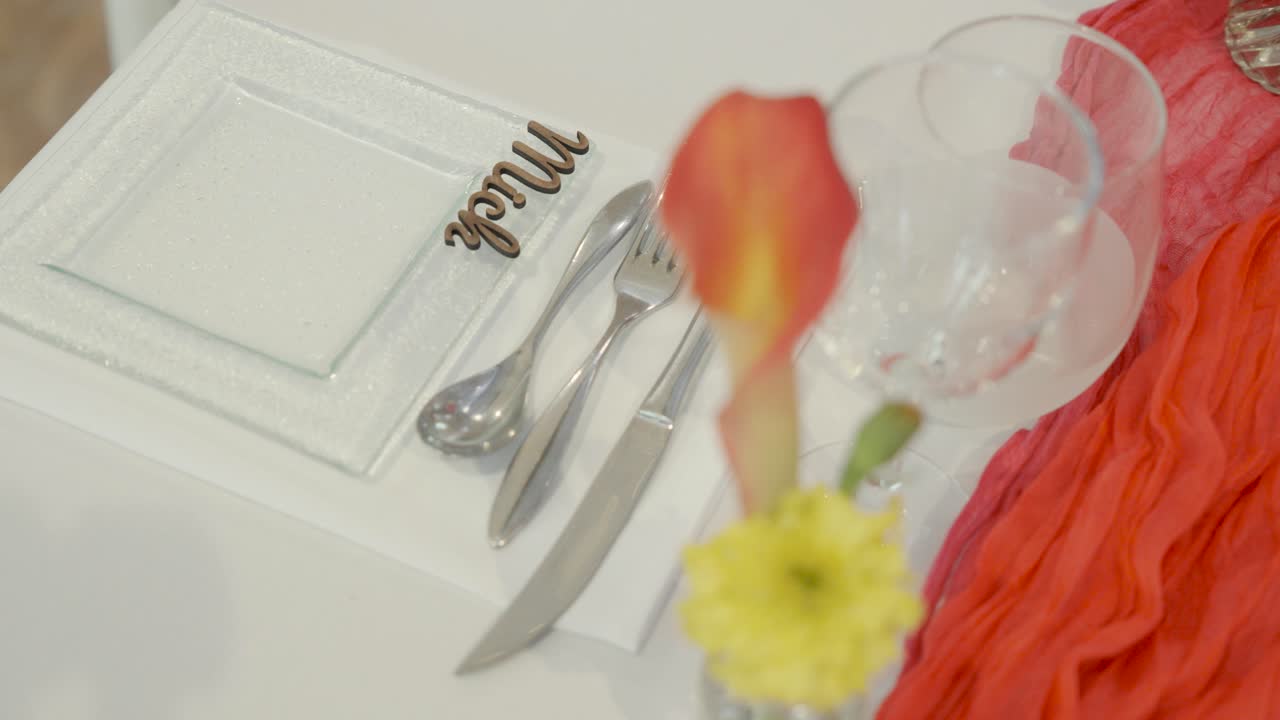 Elegant wedding table setup with cutlery, flower centerpiece, and decorative accents, capturing a refined celebration atmosphere