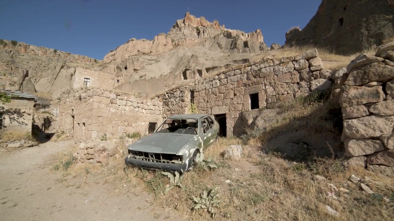 Auto abbandonata davanti ad antiche rovine in pietra in Cappadocia.