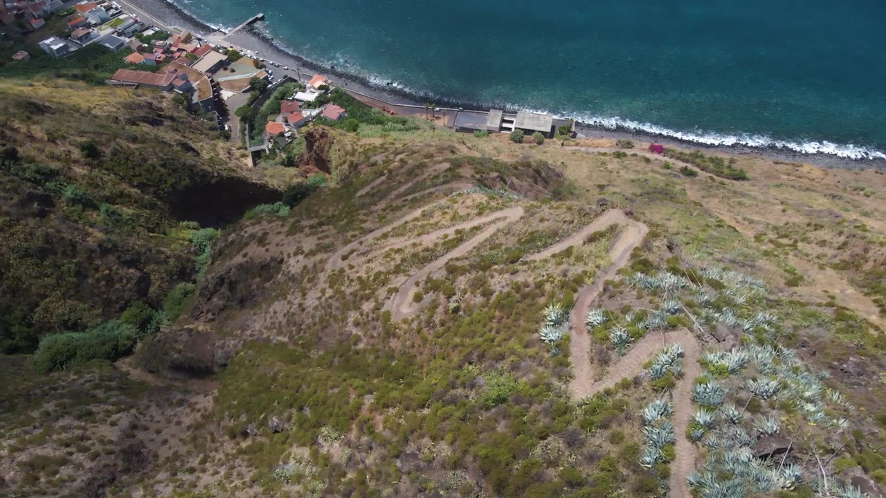Sentiero Caminho Real sopra Paul do Mar sull'isola di Madeira, che rivela uno stretto sentiero storico scavato in ripide scogliere. L'Oceano Atlantico si estende all'infinito sotto il terreno accidentato e il sentiero
