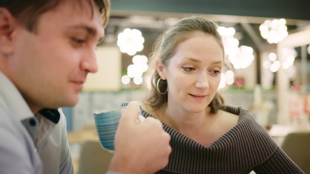 Couple Having a Conversation and Drinking Coffee in a Cafe