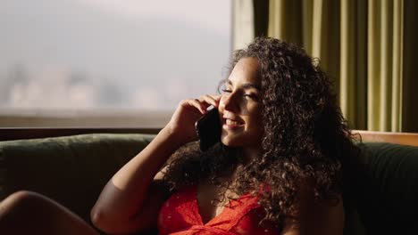 young woman with curly hair talking on the phone on a sunny day