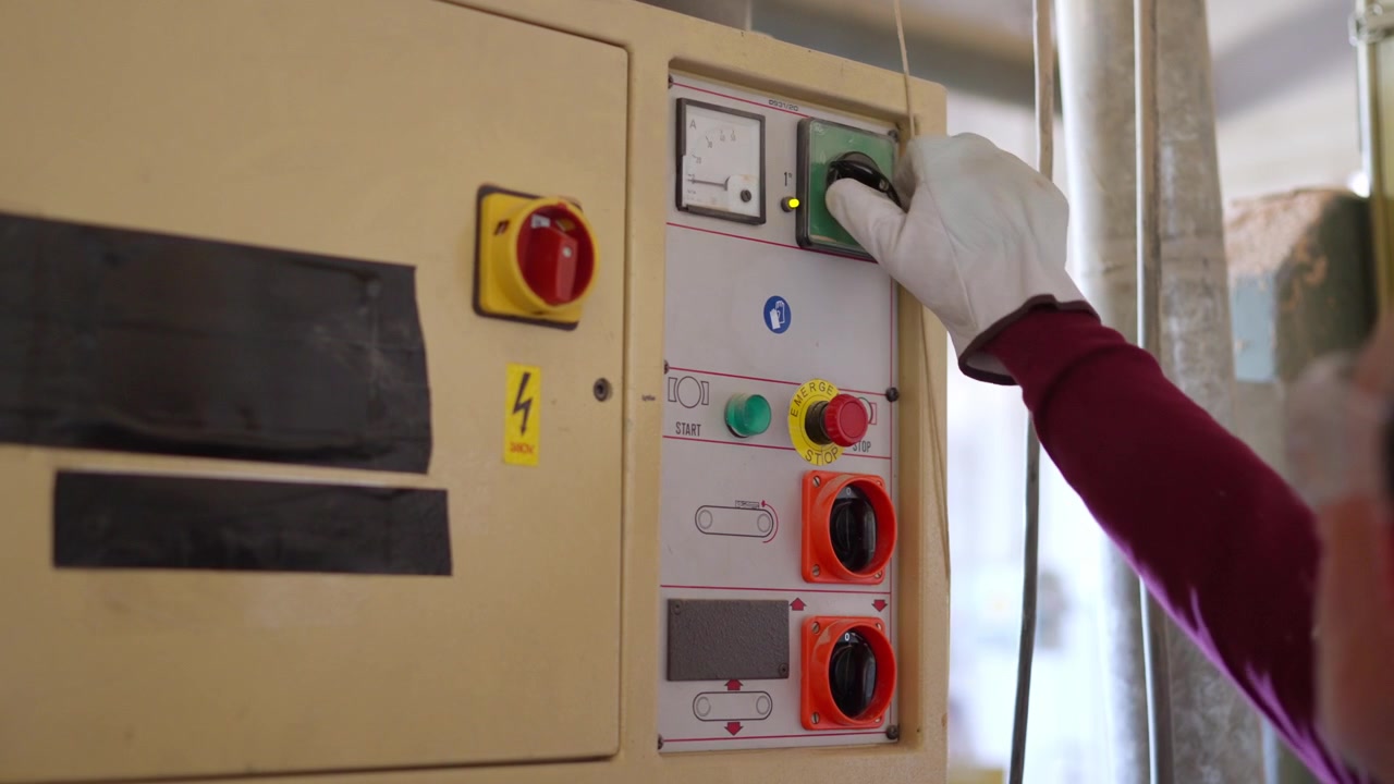 Operator hand turning on industrial machine control panel