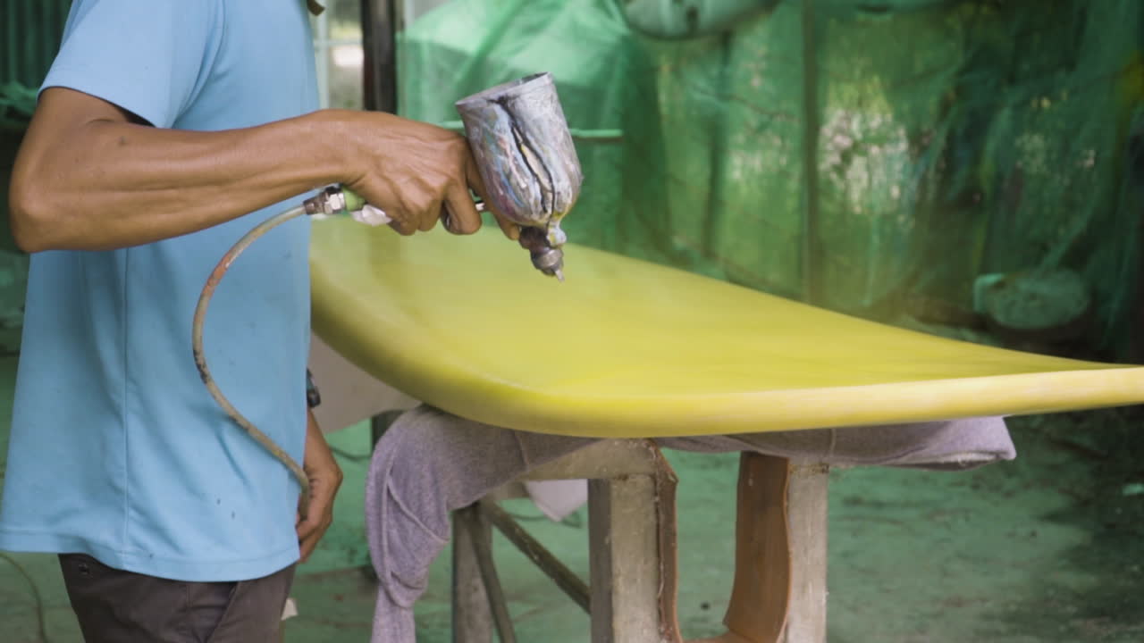 호흡기를 착용하고 가압 스프레이 페인트 총을 통해 노란색 페인트를 코팅하는 화가