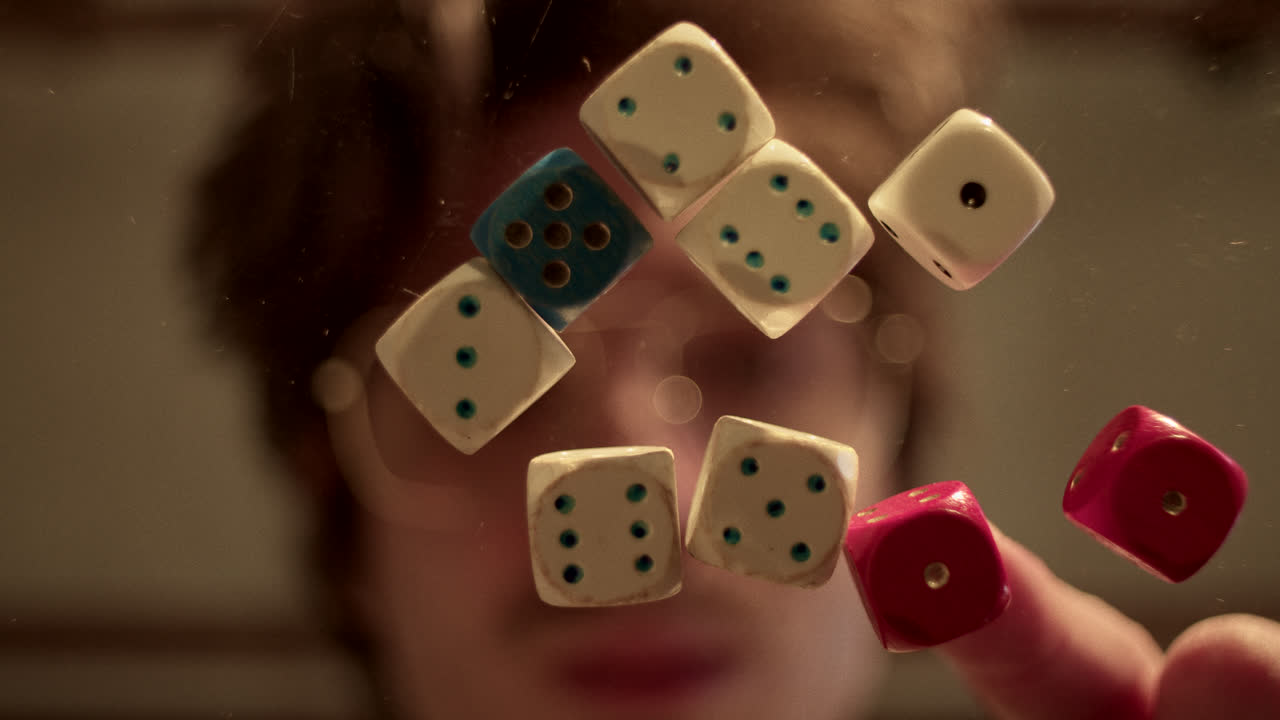 A Person Playing with Dice Reflected on a Glass Surface