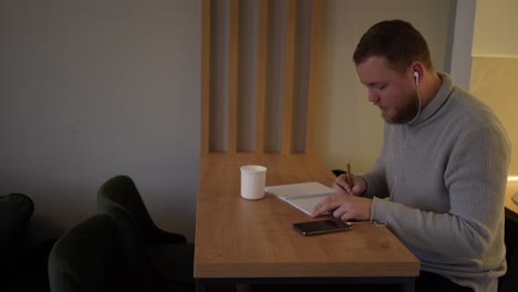 Young male influencer listening music and working